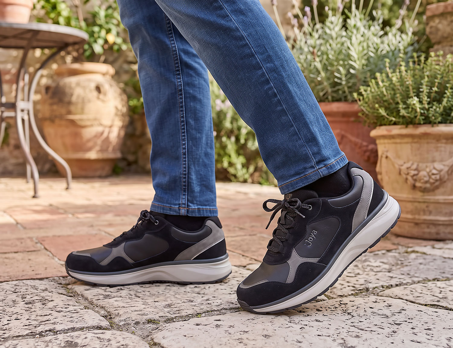 JOYA Tony III black Herrenschuh aus schwarzem Leder mit Schnürung und komfortabler Sohle, getragen beim Gehen auf Steinboden im Outdoor-Bereich