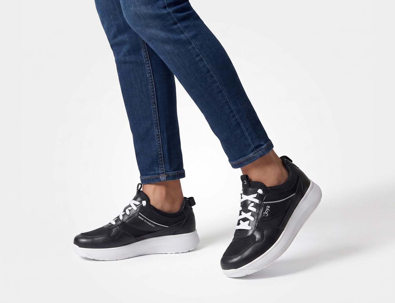 JOYA Alegra black Damen-Sneaker in Schwarz mit weißer Sohle, am Fuß getragen zu Jeans in seitlicher Ansicht