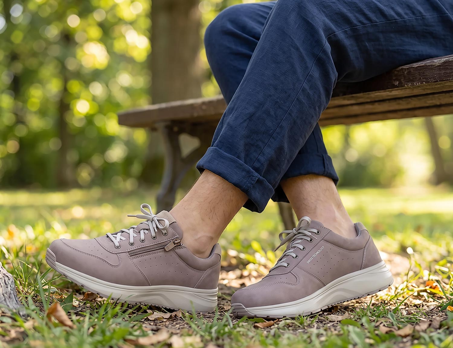 Herren tragen den JOYA DYNAMO Zip M grey II, graue Komfort-Sneaker mit seitlichem Reißverschluss und Schnürung, im Park auf einer Bank sitzend.